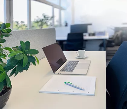 Tisch auf dem ein Laptop und ein Notizblock liegen